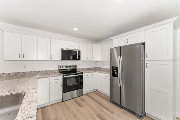 a large kitchen with a sink stainless steel appliances and cabinets