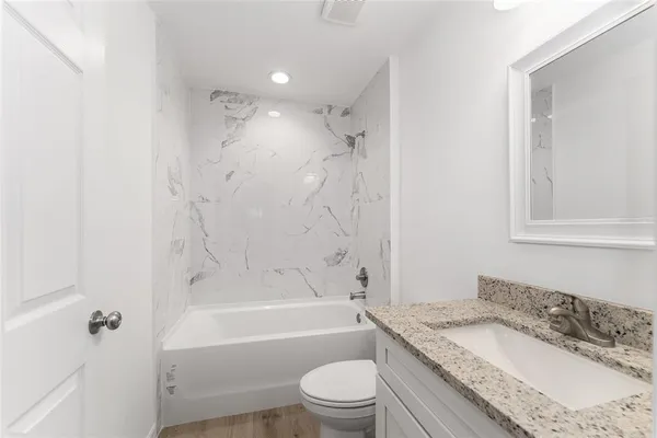 a bathroom with a granite countertop sink a toilet and bathtub