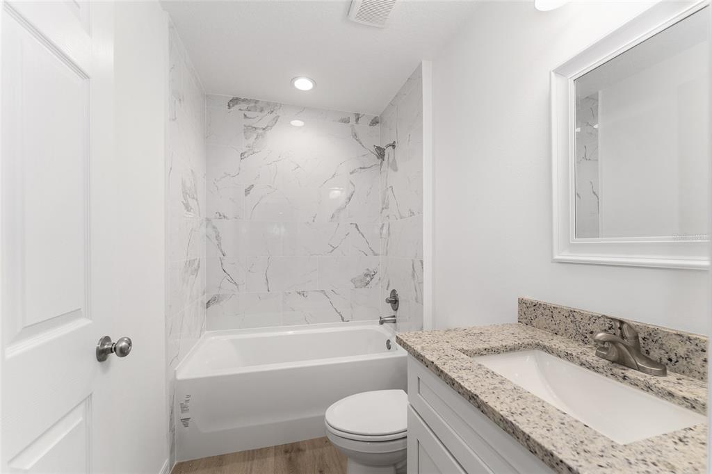 13119 Northeast 7th Loop Silver Springs, FL 34488 - Photo 34 of 51 a bathroom with a granite countertop toilet a sink and a bathtub