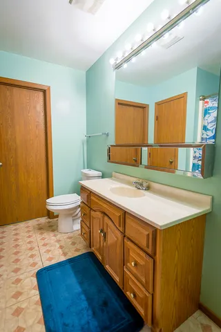 a spacious bathroom with a granite countertop sink a toilet a mirror and shower