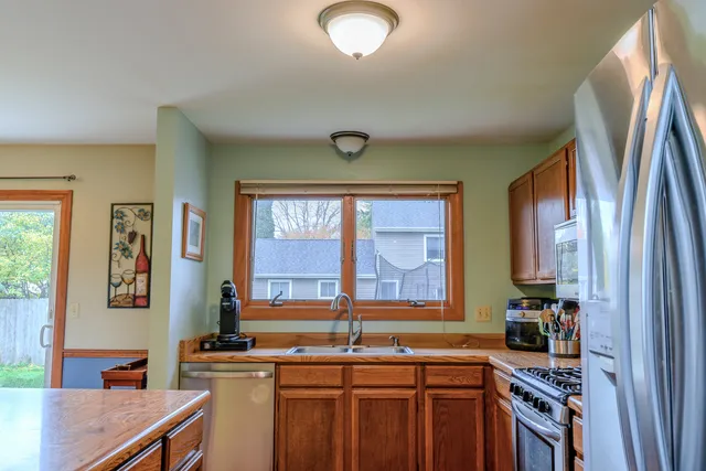 a kitchen with stainless steel appliances granite countertop a stove a sink and a refrigerator with wooden floor