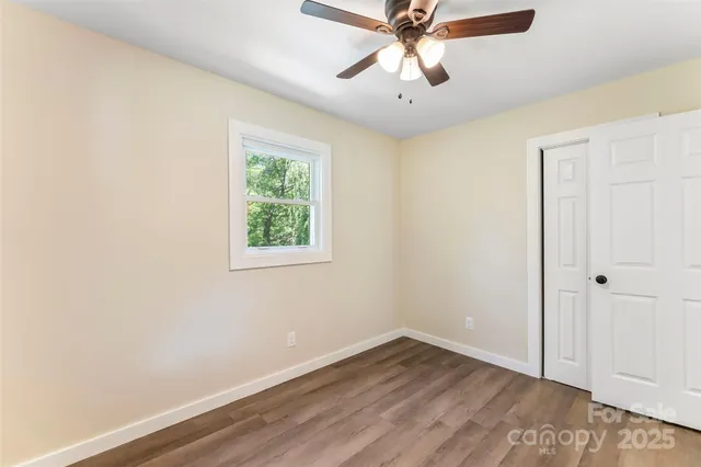 an empty room with wooden floor fan and windows
