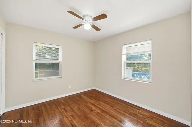 a view of an empty room with wooden floor and a window