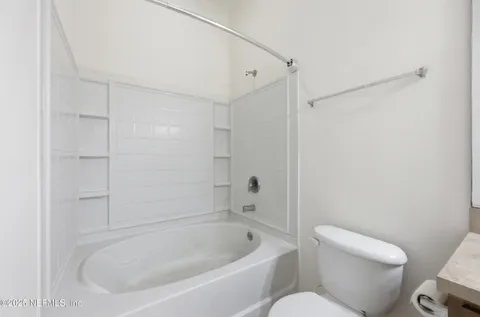a bathroom with a granite countertop sink a toilet and shower