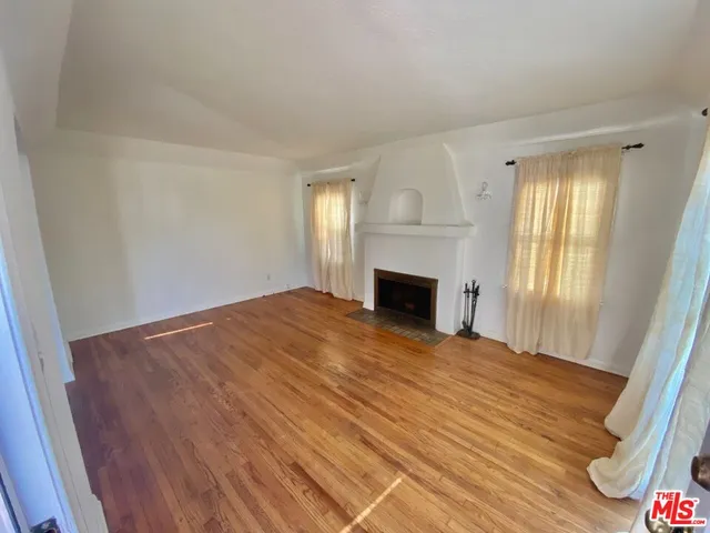 a view of empty room with wooden floor and fireplace