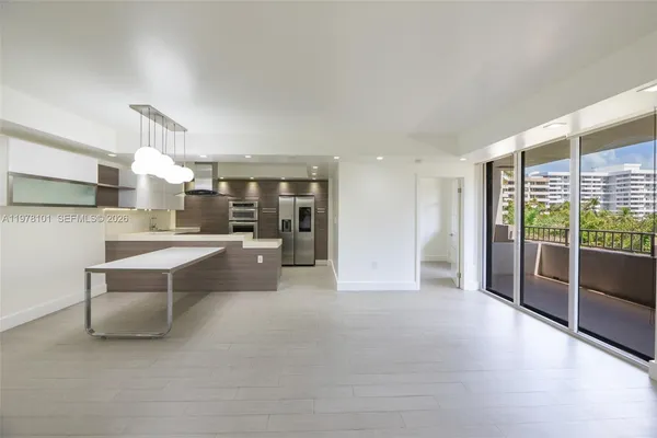 a large living room with stainless steel appliances kitchen island granite countertop a large window and a couch