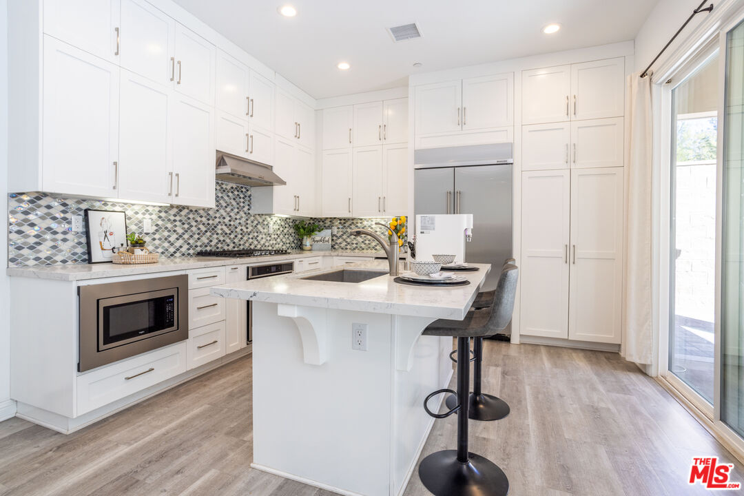 20621 West Chestnut Circle Porter Ranch, CA 91326 - Photo 5 of 30 a kitchen with kitchen island wooden cabinets and white appliances