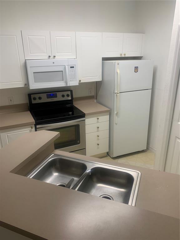 5122 Northridge Road, Unit 102 Sarasota, FL 34238 - Photo 12 of 12 a kitchen with a sink and white cabinets