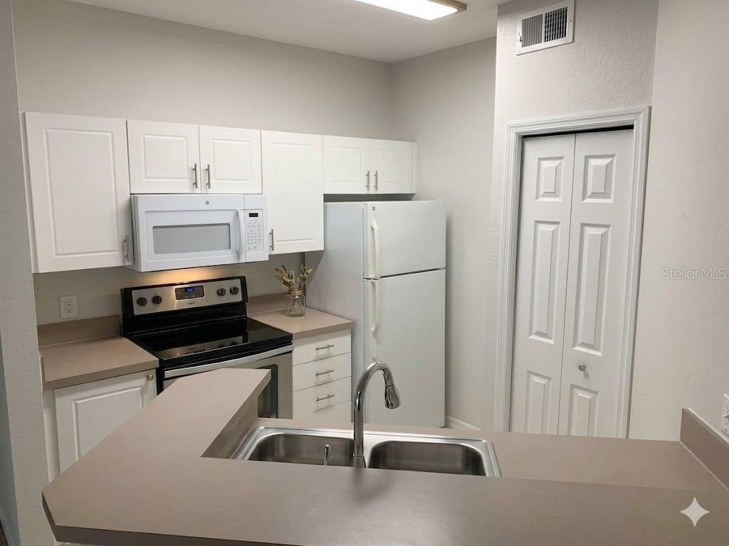 5122 Northridge Road, Unit 102 Sarasota, FL 34238 - Photo 7 of 14 a kitchen with stainless steel appliances a refrigerator sink and cabinets