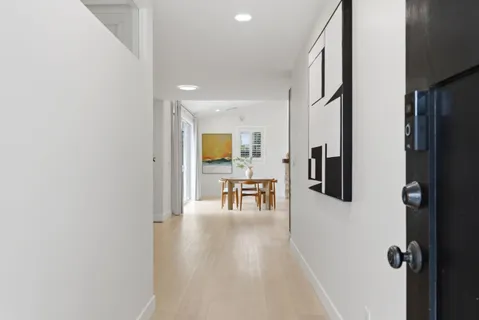 wooden floor in a hall with a window and kitchen view