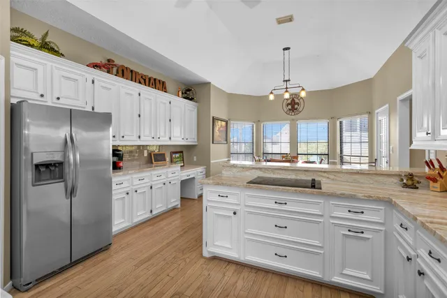 a kitchen with granite countertop white cabinets white stainless steel appliances and center island