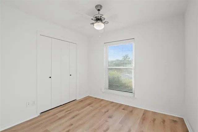 a view of an empty room with a window and a ceiling fan