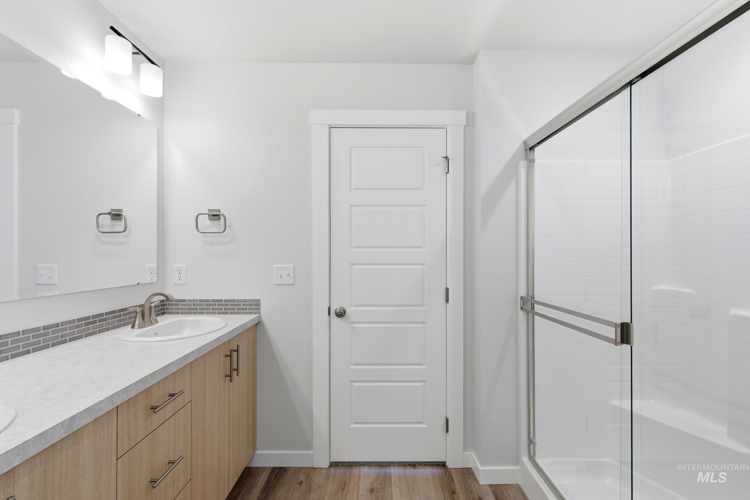 8317 South Tyrion Way Kuna, ID 83634 - Photo 22 of 22 Bathroom featuring a dual-sink vanity with light wood cabinetry and a white countertop, complemented by a gray mosaic tile backsplash