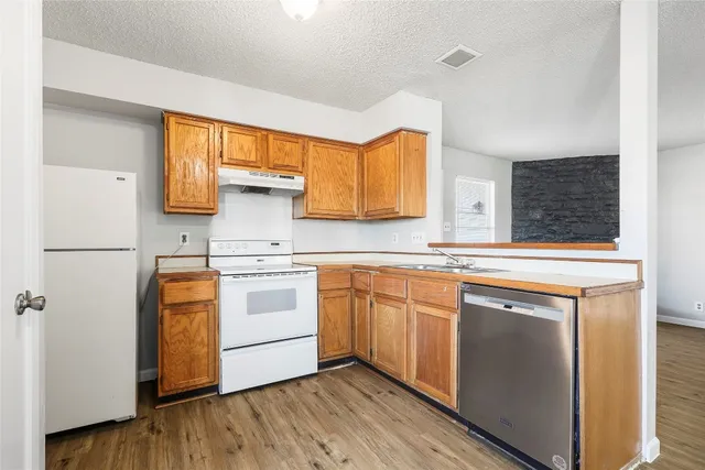 a kitchen with stainless steel appliances granite countertop a sink a stove and refrigerator