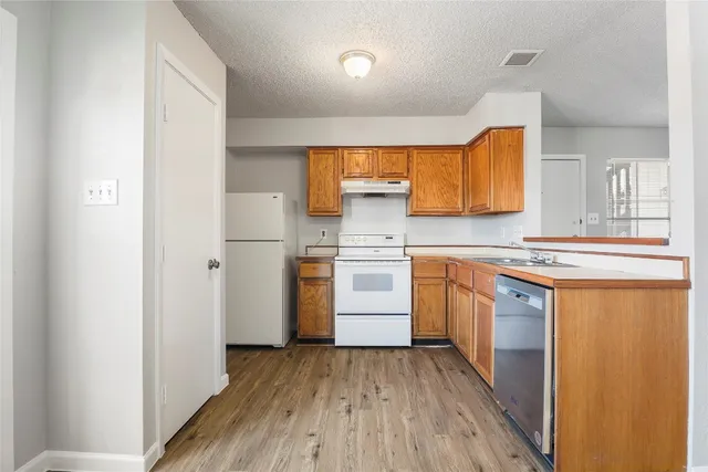 a kitchen with cabinets wooden floor and stainless steel appliances