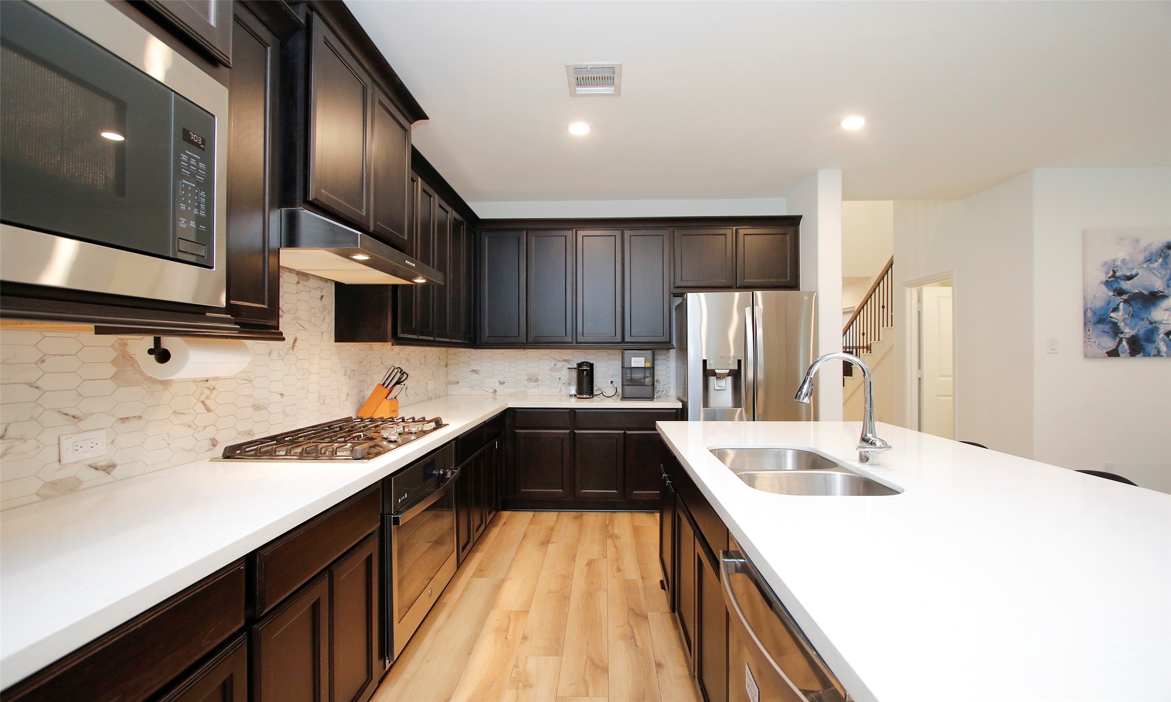 2741 Altissimo Court Spring, TX 77386 - Photo 7 of 30 High-end features include a five-burner gas cooktop, a built-in microwave, and a white hexagonal tile backsplash.
