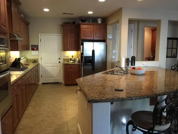 a kitchen with kitchen island granite countertop a sink stainless steel appliances and cabinets