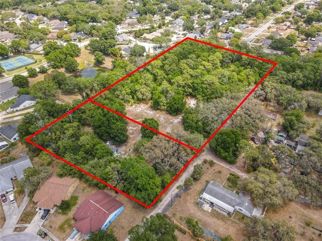 an aerial view of residential houses with outdoor space and trees