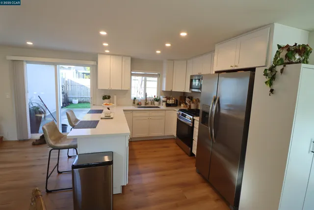a kitchen with stainless steel appliances a refrigerator a sink a stove a table and chairs