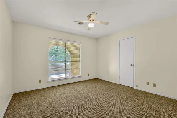 an empty room with chandelier fan and windows