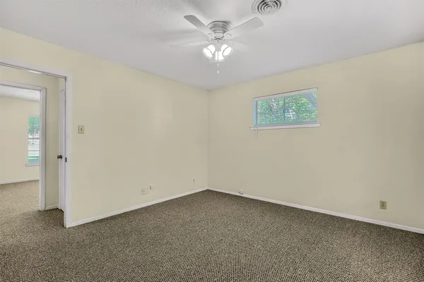 an empty room with a chandelier fan and windows
