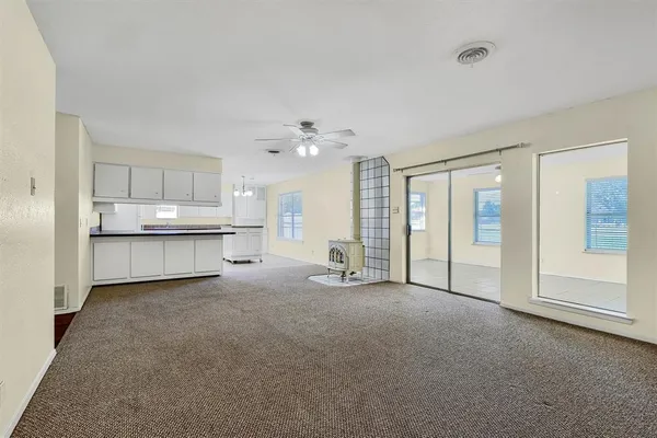 a view of an empty room with kitchen and a window