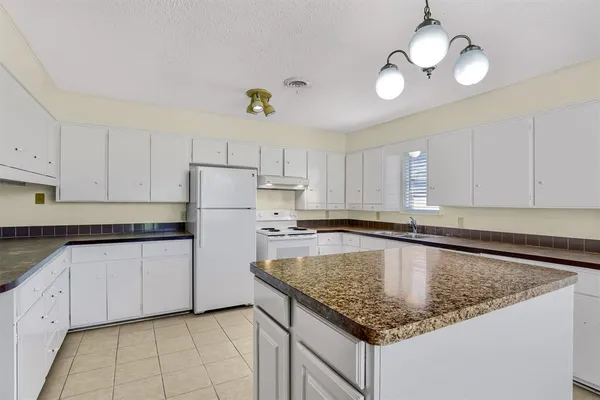 a kitchen with granite countertop a center island white cabinets and stainless steel appliances
