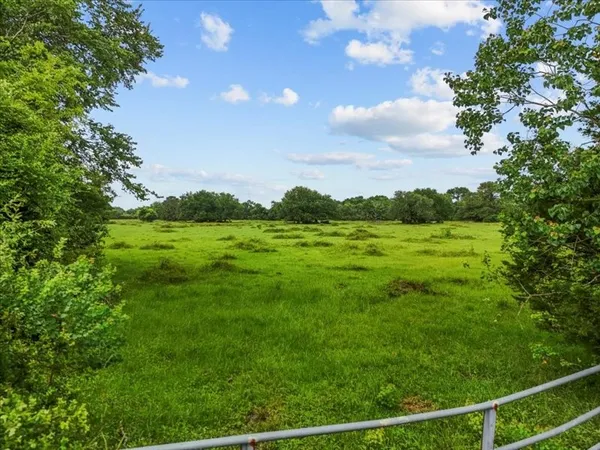 a view of a green field with wooden fence