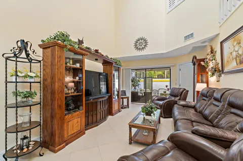 a living room with furniture a flat screen tv and floor to ceiling window