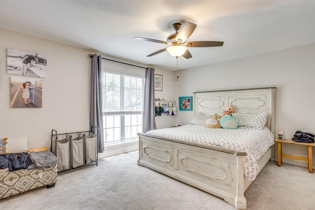 4102 Ridglea Country Club Drive, Unit 1503 Fort Worth, TX 76126 - Photo 4 of 21 Carpeted bedroom featuring a large window with blinds and drapes, a ceiling fan with integrated lighting, and neutral wall tones