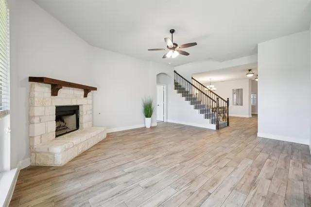 a view of an empty room with wooden floor fireplace and a chandelier