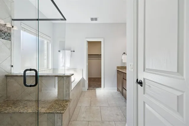 a bathroom with a granite countertop shower and a sink