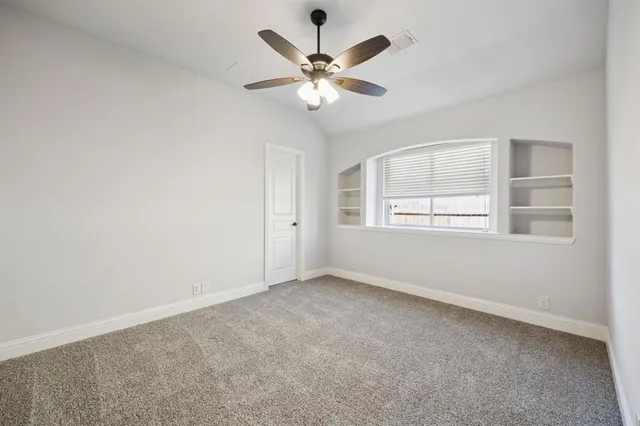 an empty room with window and ceiling fan