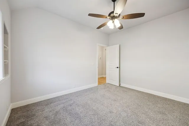 an empty room with closet and a chandelier fan