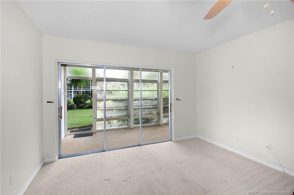 2929 Southeast Ocean Boulevard, Unit 1294 Stuart, FL 34996 - Photo 8 of 30 an empty room with wooden floor and sliding door