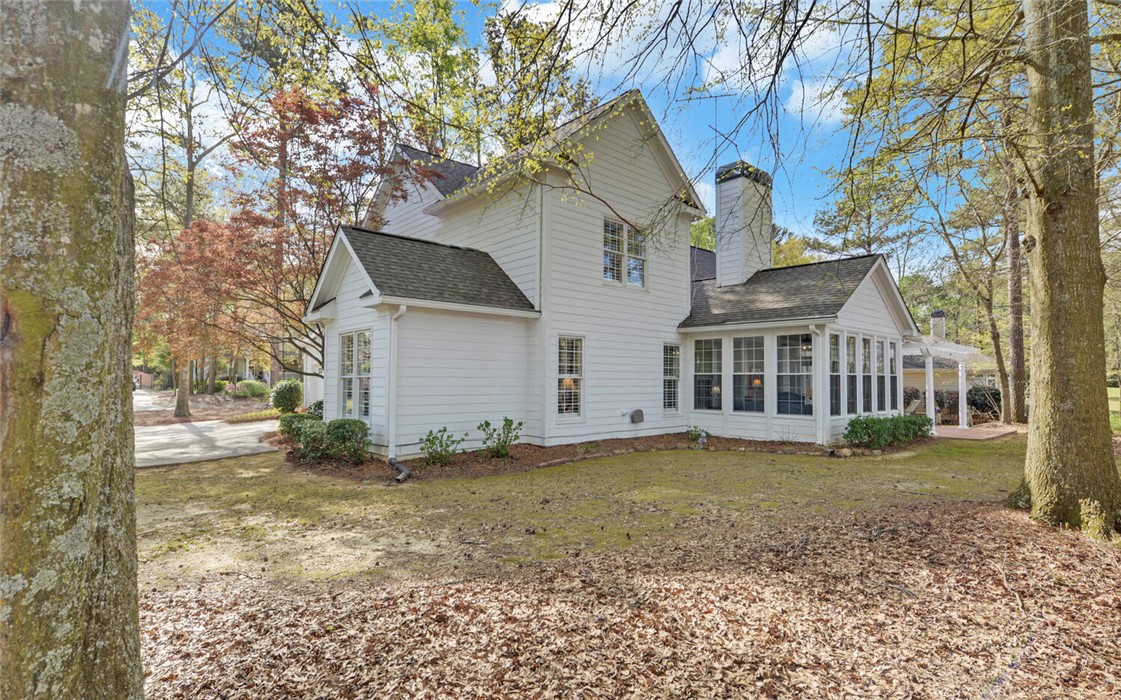 39 Azalea Drive Hartwell, GA 30643 - Photo 43 of 45 This classic white home, surrounded by lush trees, features a charming sunroom and an inviting outdoor patio.