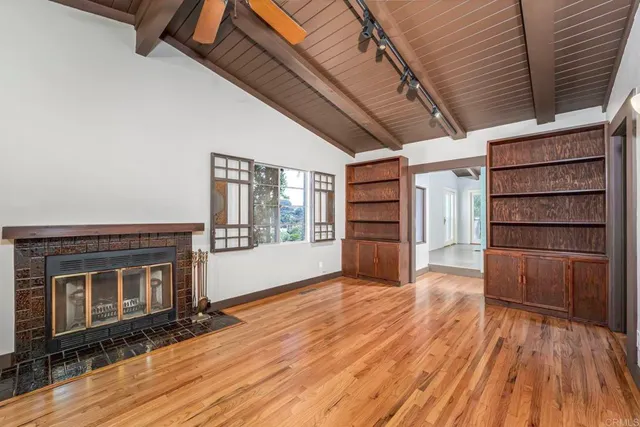 a view of an empty room with a fireplace and wooden floor