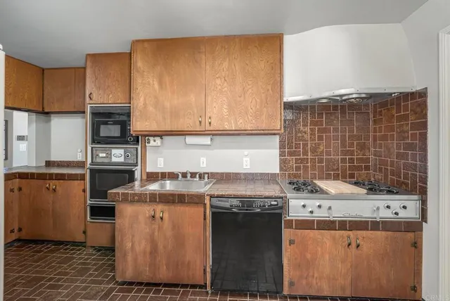 a kitchen with granite countertop a stove top oven cabinetry a sink and a refrigerator