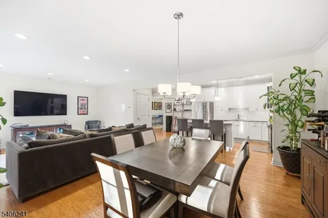 a view of a dining room and livingroom with furniture wooden floor a chandelier