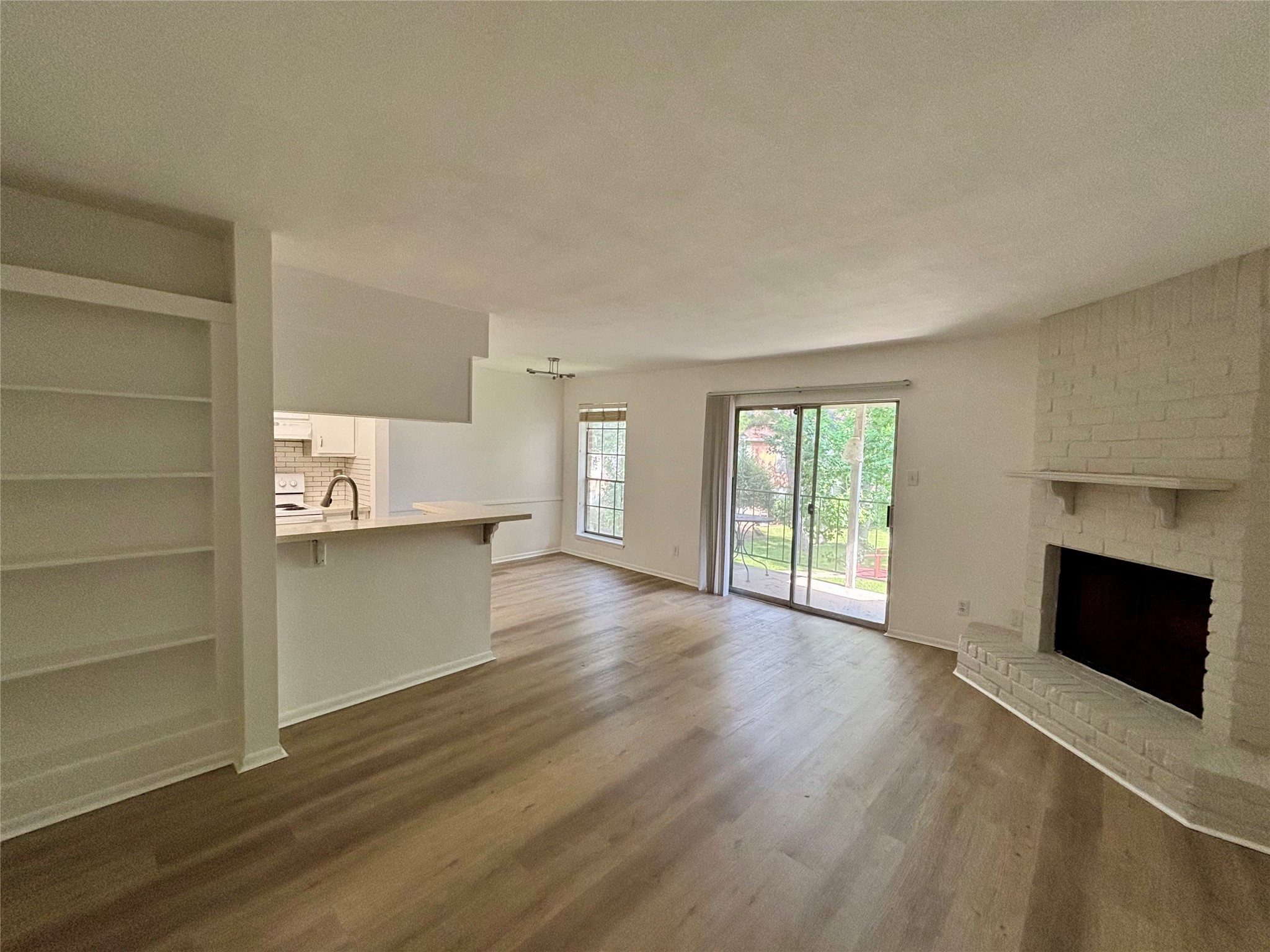 a view of a kitchen and an empty room with a fireplace