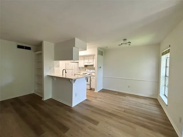 a room with kitchen island granite countertop wooden floors and white cabinets