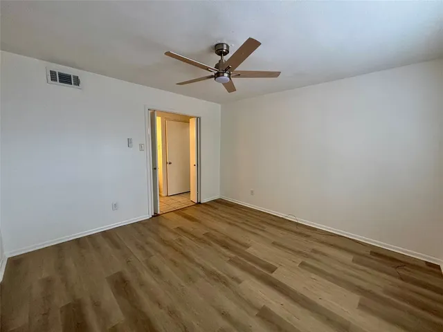 a view of empty room with wooden floor and ceiling fan