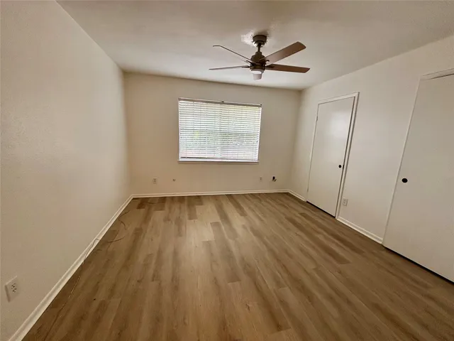 a view of empty room with wooden floor and fan