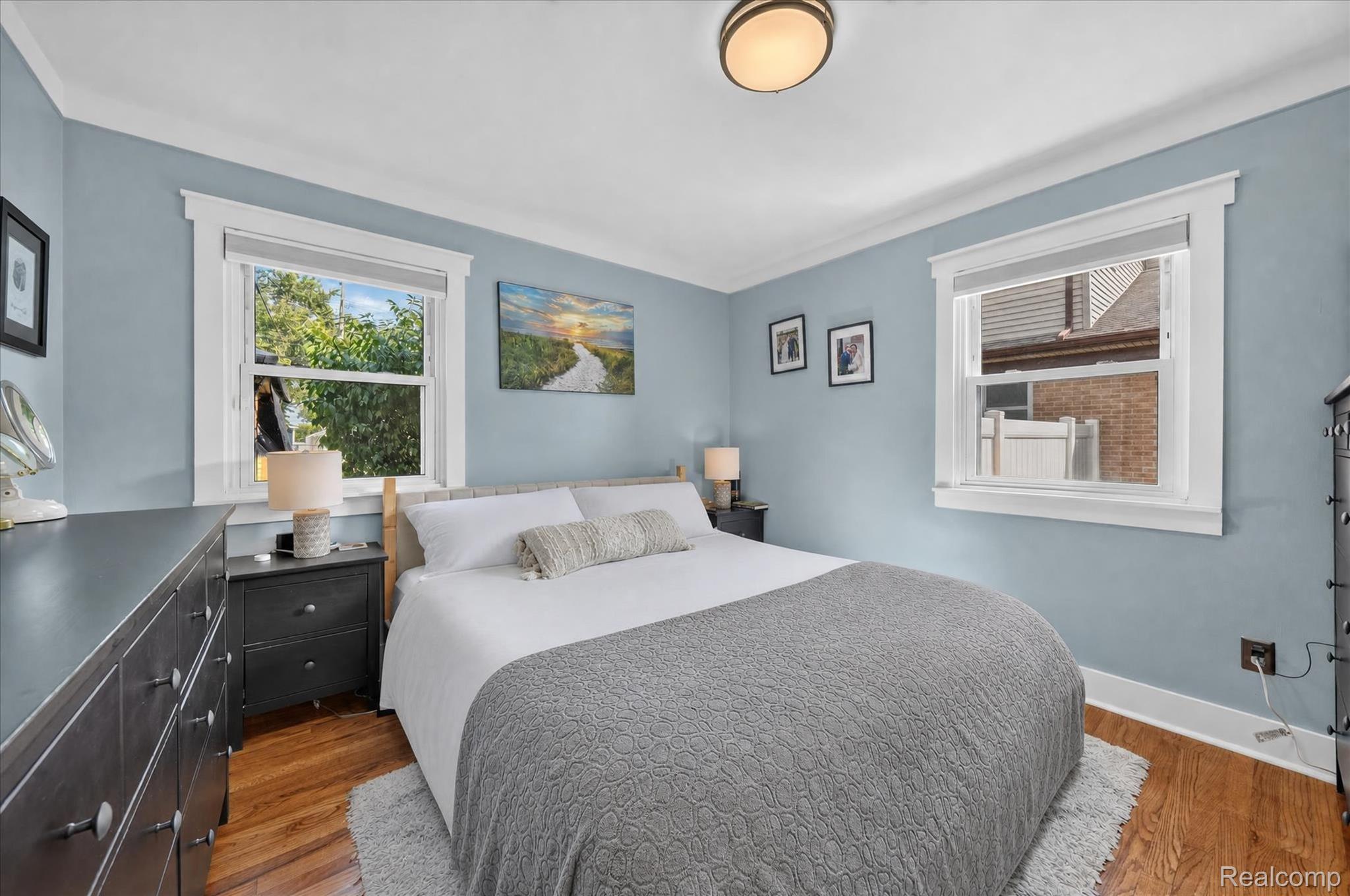 4112 Durham Road Royal Oak, MI 48073 - Photo 21 of 38 Hardwood flooring, two windows with white trim, crown molding, and a flush mount ceiling light