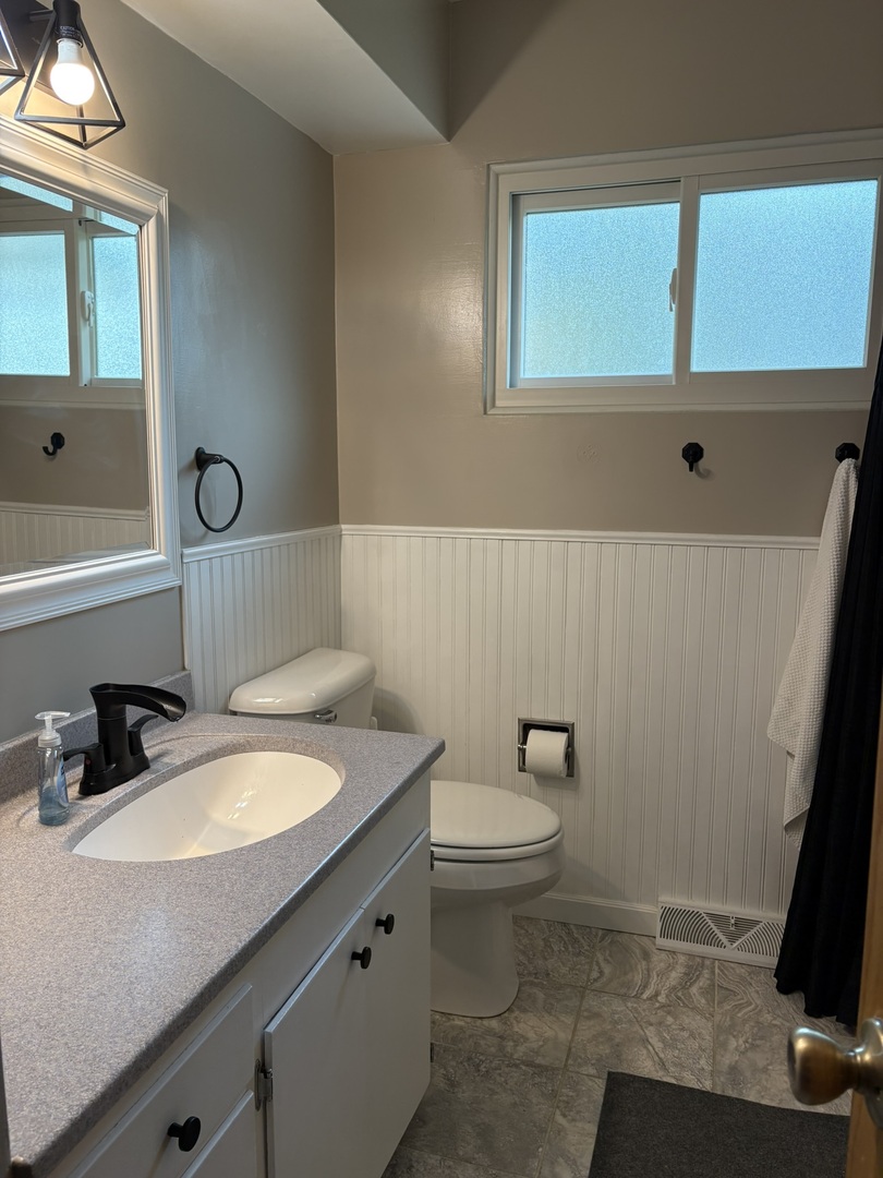 5209 12th Avenue Moline, IL 61265 - Photo 22 of 33 a bathroom with a toilet a sink a mirror and a window