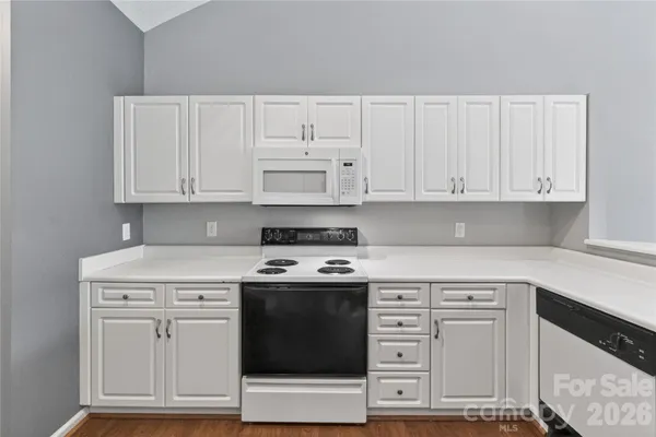 a kitchen with stainless steel appliances granite countertop a stove a sink and white cabinets