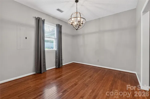 a view of an empty room with wooden floor and fan