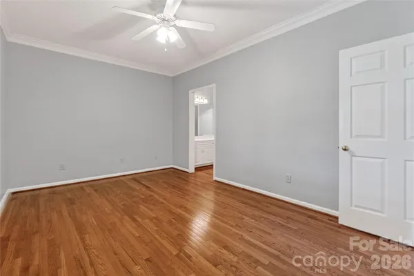 a view of an empty room with wooden floor and a ceiling fan