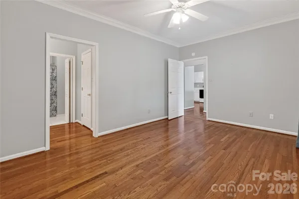a view of an empty room with wooden floor and a ceiling fan