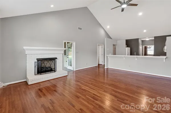 a view of an empty room with wooden floor and a fireplace